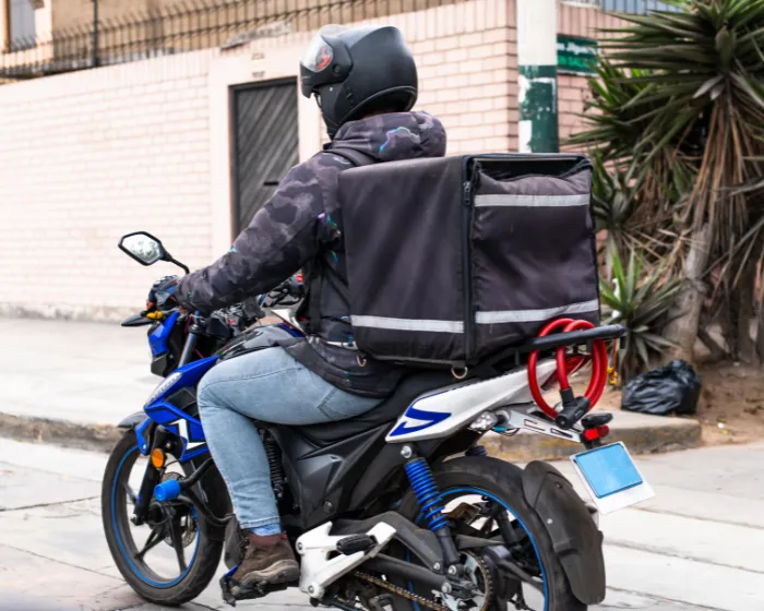 Motoboy com baú realizando entrega expressa